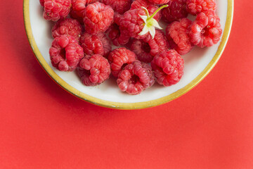 Ripe raspberry fruits on plate, healthy pile of summer berries  top view. Pattern flat lay of red scarlet  raspberry on pink background with free copy space for text