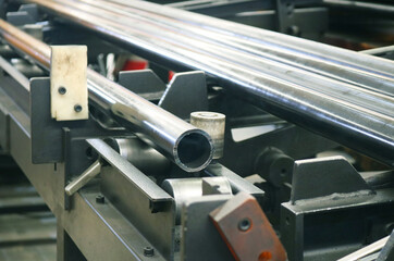 Galvanized steel round pipe on rolling machine in production process at factory.		