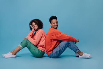 Optimistic lady and her boyfriend smile and pose sitting on blue background. Portrait of...