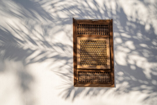 Closed window with wooden bars in an old white wall of a house on the street of Egypt in Sharm El Sheikh