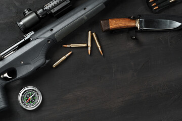 Hunting rifle and cartridges on dark wooden background