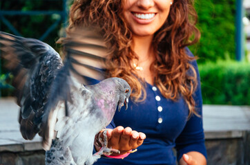 Beautiful young Latina feeding a pigeon from the palm of her hand
