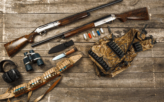 Hunting equipment on old wooden background including rifle, knife, binoculars and cartridges