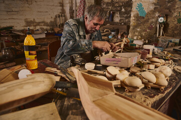Making wooden toys in workshop, craftsman in action, old artist at work