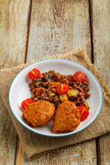 Cod cutlets with stewed potatoes and vegetables on a plate on a napkin on the table.