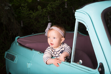 Surprised  baby girl sitting in a car and looking out of the window. Funny little driver.