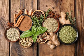 Flat lay composition with different natural spices and herbs on wooden table