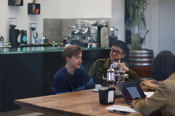 two relaxed friends during work break drink coffee in office while chatting