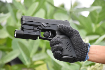 Automatic 9mm pistol which has flashlight under the muzzle holding in hand and ready to shoot,...