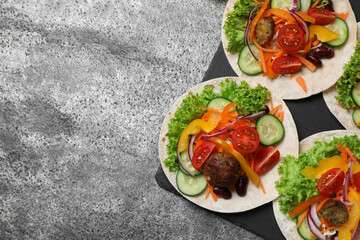 Many delicious vegetarian tacos served on grey table, flat lay. Space for text
