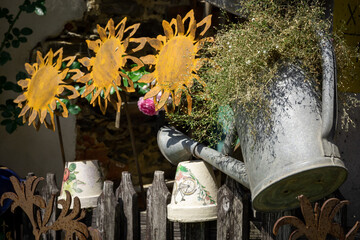 A vintage watering can, flowers and pots hanging on a wooden fence. 