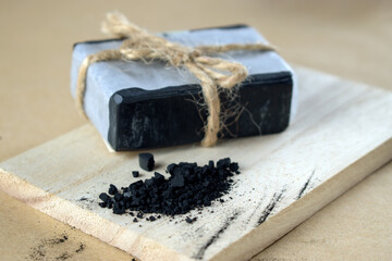 Block of natural carbon soap on a wooden board.