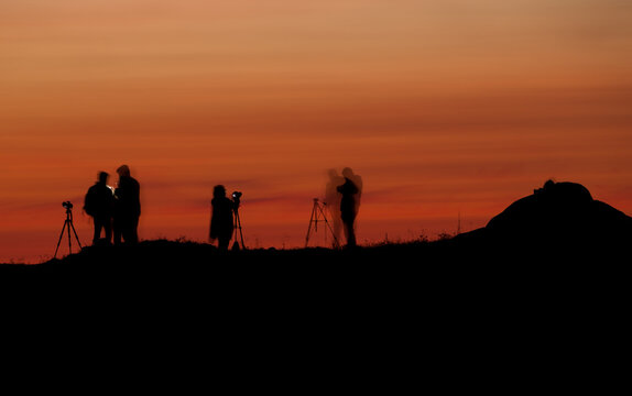 Silhouettes of people in a photography workshop during sunset. Long exposure shot.