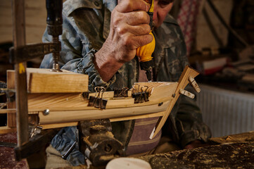 Craftsman sticking wooden details on a sailboat in his own workshop. Carpenter in action, lifestyles, hobby concepts