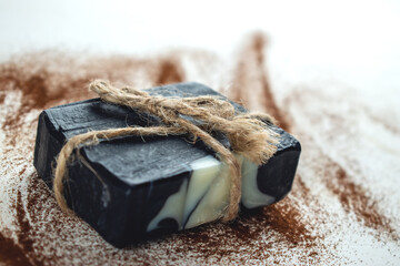 A block of natural carbon soap on a white background sprinkled with coffee