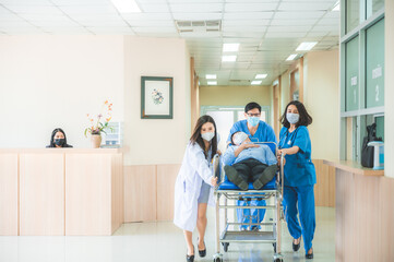 Emergency department,  medical team with doctors, nurses and surgeons are pushing seriously injured patient emergency stretcher bed in the hospital corridor