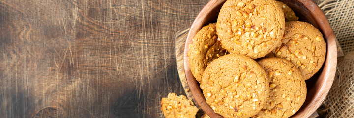 Healthy homemade oatmeal cookies with peanuts in a wooden bowl on a brown kitchen table top view...