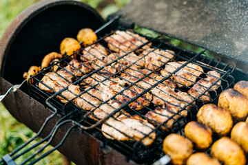 Barbecue with meat and mushrooms fried on the grill outdoors on back yard. Mushrooms on skewers are fried on charcoal.