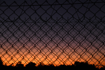 Beautiful view of the colorful skies during the sunset and the metal fence in front of it