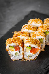 appetizing philadelphia sushi roll with tuna salmon avocado chips and cucumber on a black stone plate