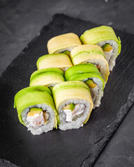appetizing green dragon sushi roll with philadelphia cucumber shrimp and avocado on a black stone plate