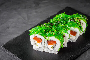 appetizing sushi roll with philadelphia cheese cucumber salmon and chuka on a black stone plate