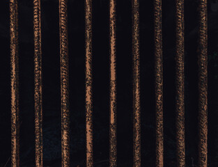 Closeup shot of old rusty thin metal bars on a black background