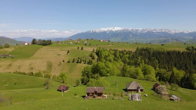 Birds eye view over lovely village of Pestera in Brasov county, Romania. Drone footage over the village with mountains in the background.