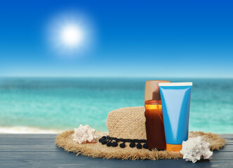 Skin sun protection products and hat on blue wooden table against seascape. Space for design