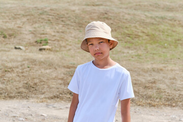 Portrait of an Asian boy in a white T-shirt and a panama hat