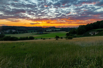Long exposure image of an amazing sunset over the valley in Maastricht with a dramatic sky, showing amazing colors and impressive landscape views with on a view of Devils cave a former quarry