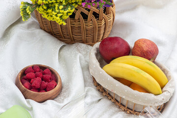 Fruit at a picnic. A basket of fruits next to a basket of flowers. Camping.