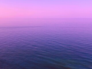 Pink sky sunrise over blue sea water. Dawn over calm rippled ocean waves. Pink sky sunrise over...