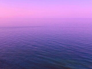 Pink sky sunrise over blue sea water. Dawn over calm rippled ocean waves. Pink sky sunrise over blue sea water. Dawn over calm ocean waves. Fantasy, fairy tale, surreal landscape, magical ocean.