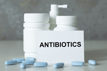 Card with text ANTIBIOTICS on the table next to the pill cans. Medical concept.