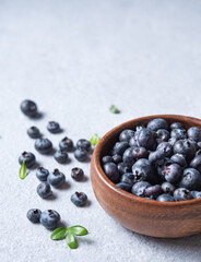 sweet fresh blueberries in a wooden  bowl  on a blue background. Macro and close up  view and copy space