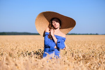 Girl in wide hat in wheat field