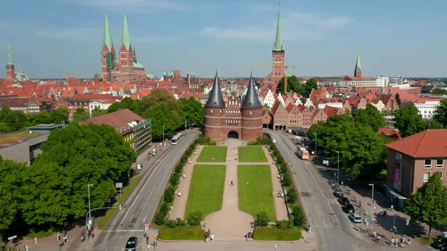 Tilt up forwards reveal of historic centre of town. Red brick houses, churches and buildings. Fly between towers of Holsten Gate. Luebeck, Schleswig-Holstein, Germany