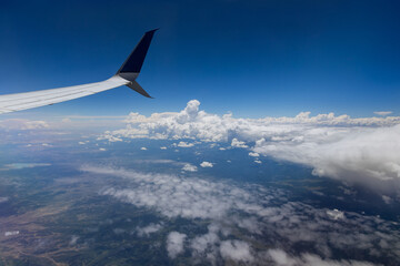 Airplane wing view out of the window on the cloudy sky the earth background