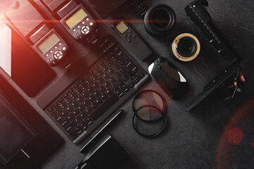 Professional Photographic Equipment.Digital photo workstation over black background.Top view of  digital camera, flash,lens and laptop.