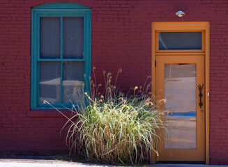 Close up of a side of a building where a color door, window and brick stand out.