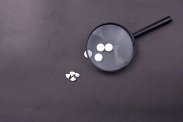 magnifying glass with black handle and pills