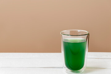 Green chlorophyll drink in a glass on white table with copy space