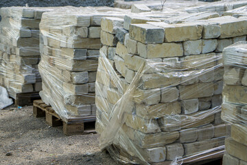 bricks are stacked in a square pile, sealed in cellophane. Construction Materials