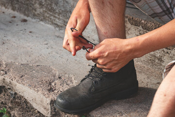 tying laces of boots outdoors. Concrete steps.