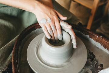 A female craftsman works in a clay workshop on a potter's wheel. The concept of creative people.