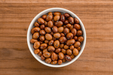 Beans in a Ceramic Bowl. These nutritious legumes are high in protein and fiber. The image is a cut out, isolated on a wood background