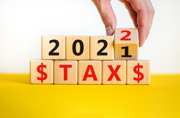 Business concept of tax planning 2022. Businessman turns wooden cube and changes words 'Tax 2021' to 'Tax 2022'. Beautiful white background, copy space. Business, 2022 tax concept.