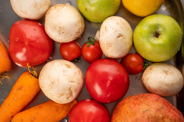 clean vegetables and fruits lie on a metal kitchen tray