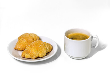 sweet homemade shortcrust pastry bagels on a porcelain plate and a cup of coffee on a white surface